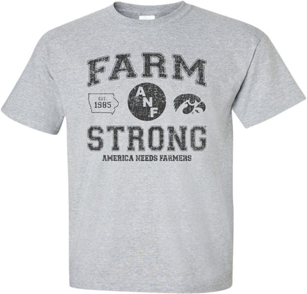 A light gray short-sleeve t-shirt with a distressed black design on the front that reads 'FARM STRONG' with 'AMERICA NEEDS FARMERS' underneath, alongside the ANF logo and the Iowa Hawkeyes Tigerhawk logo.